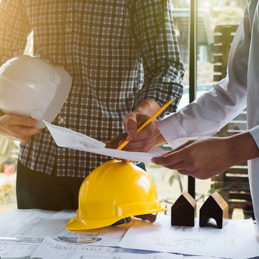 2 individuals looking over construction blueprints