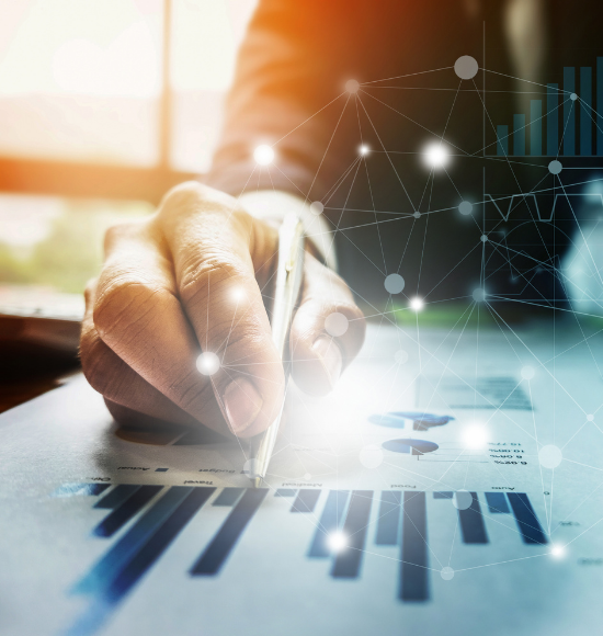 man with pen in hand looking at graphs on a piece of paper